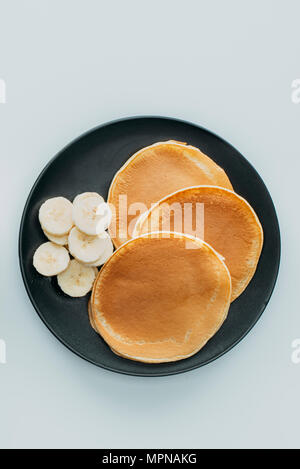 Vista dall'alto di gustosi pancake con fette di banana sul tavolo bianco Foto Stock