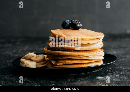 Deliziosi pancake impilati con mirtilli e fette di banana Foto Stock