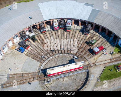 05.05.2018, Brandeburgo, Wittenberge: una locomotiva diesel si erge sulla tavola della locomotiva storica capannone. (Vista aerea con un drone) nel 2010, la città di Elba aveva acquisito il settore ferroviario e messo quasi tre milioni di euro per la ristrutturazione delle ex deposito e le circa 2,5 chilometri di piste. Nel semicerchio edificio in mattoni costruito intorno al 1895, sono oggi in 16 spazi di parcheggio in media oltre 80 anni di locomotive restaurata dall'hobby ferroviario. Foto: Jens Buttner/dpa-Zentralbild/ZB | Utilizzo di tutto il mondo Foto Stock