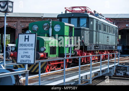 05.05.2018, Brandeburgo, Wittenberge: una piccola locomotiva diesel tira l'unica locomotiva elettrica del museo ferroviario Wittenberge Lokschuppen sulla piattaforma girevole. Nel 2010, il Elbe-Stadt aveva acquisito il settore ferroviario e messo quasi tre milioni di euro per la ristrutturazione delle ex deposito e le circa 2,5 chilometri di piste. Nel semicerchio edificio in mattoni costruito intorno al 1895, sono oggi in 16 spazi di parcheggio in media oltre 80 anni di locomotive restaurata dall'hobby ferroviario. Foto: Jens Buttner/dpa-Zentralbild/ZB | Utilizzo di tutto il mondo Foto Stock