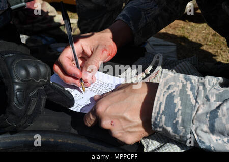 Tech. Sgt. Christian Gomez, 569th U.S. Le forze di polizia Bravo Squadron capo di volo, scrive il ferimento di un ferito simulato Airman durante il combattimento tattico casualty care porzione di 435th delle forze di sicurezza lo squadrone di massa del Combat Readiness Training Center di operazioni di sicurezza Corso su Ramstein Air Base, Germania, 30 marzo 2017. Durante la porzione di TCCC, gli studenti dovevano lavorare insieme per proteggere la zona, fornire aiuto alla vittima simulato, chiamata per un evacuazione medica, spostare la vittima su di una lettiera e caricarli in una simulazione di elicottero. Avieri assegnato per la 86fs, 422S Foto Stock