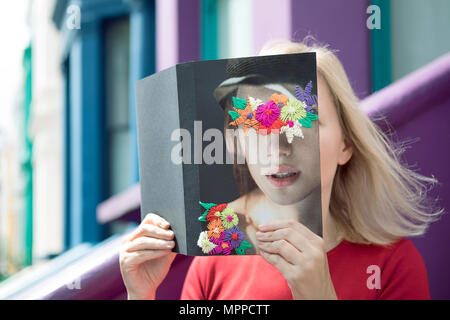 Donna che ricopre la faccia con il libro e la lettura di poesie in città Foto Stock