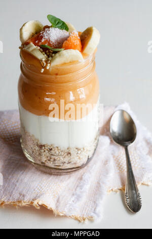 Bicchiere di cereali, yogurt naturale, papaia Smoothie guarnita con frutta e fiocchi di cocco Foto Stock