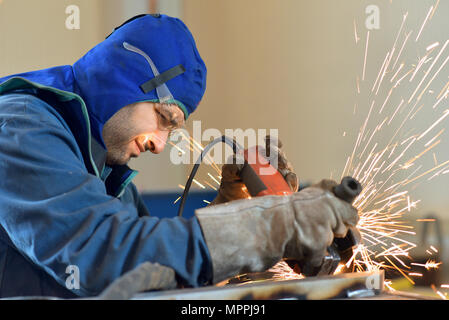 Lavoratore utilizzando smerigliatrice angolare in fabbrica Foto Stock