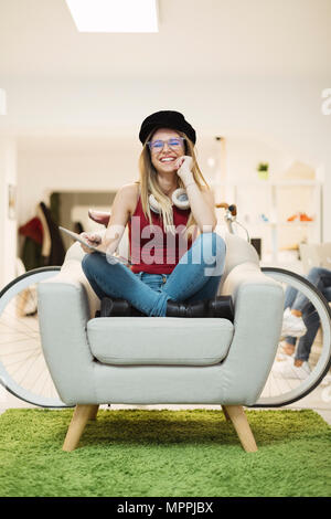 Felice casual giovane donna con la compressa in coworking space Foto Stock