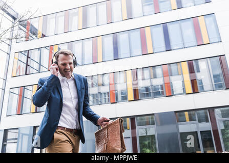 Happy businessman ascolto di musica con cuffie Foto Stock