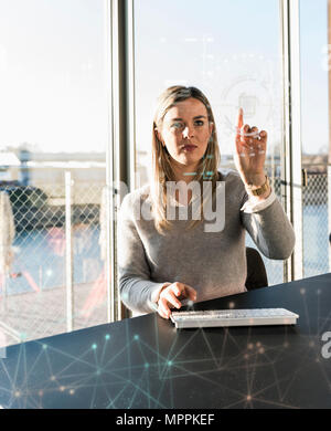 Giovane imprenditrice toccando lo schermo di proiezione con i dati di office Foto Stock