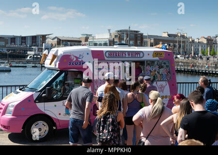 I turisti in vacanza in coda per gelati a partire da un tradizionale British ice cream van su una calda estate bank holiday nella Baia di Cardiff, Cardiff, Galles, UK. Foto Stock