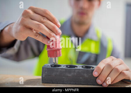 Close-up di elettricista e mettere il tappo nella striscia di alimentazione Foto Stock