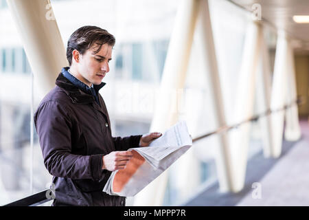 Imprenditore in piedi di skywalk quotidiano di lettura Foto Stock