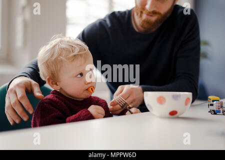 Padre alimentando il suo piccolo figlio con pasta Foto Stock