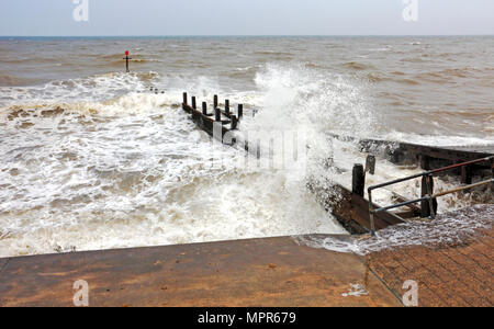 Onde che si infrangono contro un frangiflutti e seawall sulla costa di Norfolk a Walcott, Norfolk, Inghilterra, Regno Unito, Europa. Foto Stock