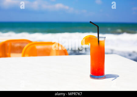 Bicchiere da cocktail sul mare sullo sfondo. Tequila Sunrise Foto Stock