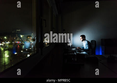 Imprenditore lavorando sul computer in ufficio scuro Foto Stock