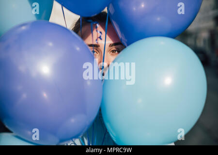 La donna si nasconde dietro i palloncini blu Foto Stock