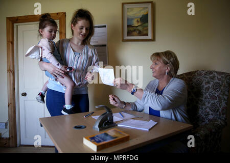 Residente di Gola Isola Colleen Ui Fhioruisce con sua figlia Saoirse (2) riceve la sua scheda di polling da Nancy Sharkey, presiedere Officer per la Gola isola, prima della colata il suo voto come isolani di andare alle urne con un giorno di anticipo del resto del paese per esprimere il loro voto al referendum sull'Ottavo emendamento della Costituzione irlandese. Foto Stock