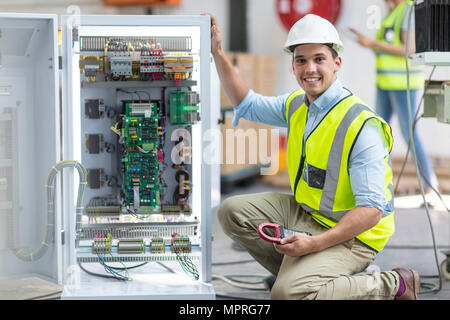 Ritratto di sorridere tecnico che lavora su una scatola con le schede di circuito Foto Stock