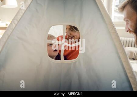 La famiglia felice giocando in una tenda a casa Foto Stock