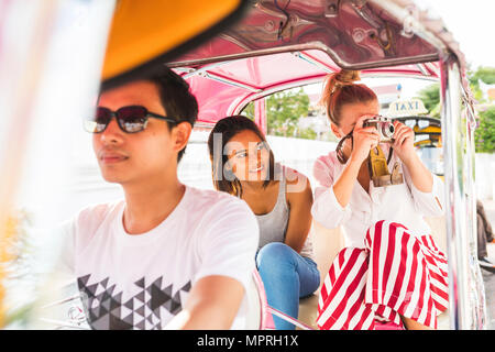 Thailandia, Bangkok, amici equitazione tuk tuk a scattare foto con una vecchia macchina fotografica Foto Stock