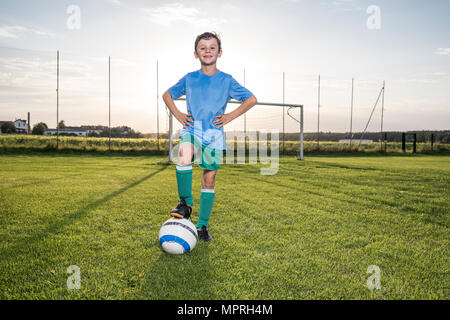 Ritratto di fiducioso giovane calciatore con la palla sul terreno di calcio Foto Stock