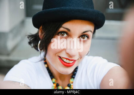 Ritratto di donna sorridente con hat tenendo selfie Foto Stock