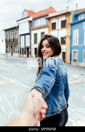 Ritratto di un sorridente brunette donna tenendo in mano una città Foto Stock