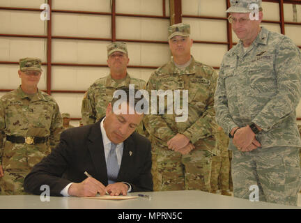 Nevada Gov. Brian Sandoval, seduto, emana un pro-Nevada Guard bill in legge mentre Nevada leadership di guardia funzionari guardare a conclusione di un Welcome Home Cerimonia per circa 180 Nevada guardia esercito di soldati di segnale il 9 aprile a Reno, Nev. Foto Stock