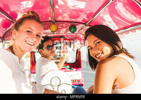 Thailandia, Bangkok, ritratto di sorridere amici equitazione tuk tuk Foto Stock