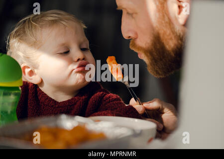 Padre alimentando il suo piccolo figlio con gustosi piatti di pasta Foto Stock