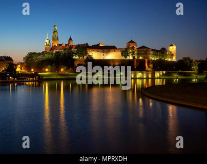 La Polonia, Cracovia. Illuminata castello reale di Wawel e Cattedrale di notte e i riflessi di luce nel fiume Vistola. Riverside con park, alberi, promenade, l Foto Stock