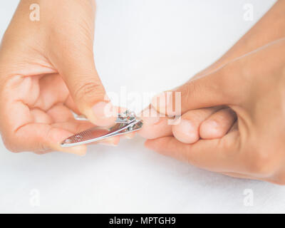 Closeup attraente giovane donna il taglio i suoi piedi unghie. La cura per la salute e la bellezza del concetto. Foto Stock