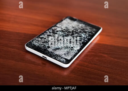 Mobile per Smartphone con uno schermo rotto. Legno di sfondo. Telefono concetto di riparazione. Il vecchio telefono rotto con schermo nero. Display incrinato nella forma di Foto Stock