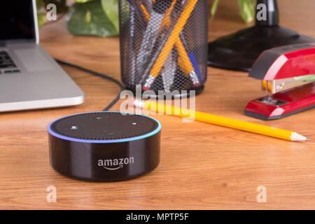 Amazon eco dot, un viva voce dispositivo controllato che si collega alla Alexa servizio vocale su una scrivania in legno Foto Stock