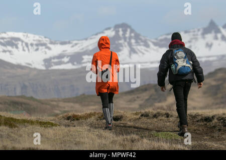 Coppia birdwatching; Walkers nella riserva naturale di Djúpivogur, maggio neve freddo paesaggi in Islanda. Foto Stock