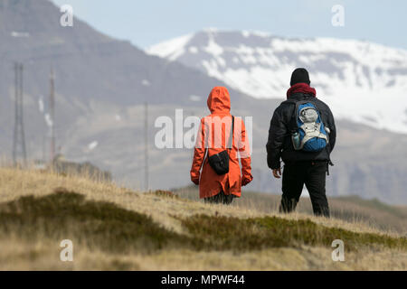 Coppia birdwatching; Walkers nella riserva naturale di Djúpivogur, maggio neve freddo paesaggi in Islanda. Foto Stock