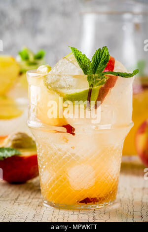 Pesca e Limonata di lime, cocktail mojito con frutta fresca guarnire, om luce sfondo concreto spazio copia messa a fuoco selettiva Foto Stock