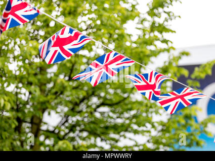 Unione Jack bunting turbinano nella brezza celebrando British evento esterno con alberi in background nel Regno Unito Foto Stock