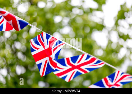 Unione Jack bunting turbinano nella brezza celebrando British evento esterno con alberi in background Foto Stock