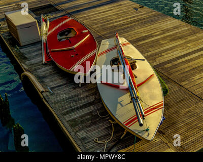Due barche a vela personali sedersi sul dock a Liberty Marina di atterraggio in primavera. Alla fine del giorno luce dorata migliora la loro bellezza. Foto Stock