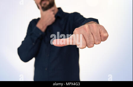 Uomo in camicia blu facendo mano gesto con il pollice lateralmente Foto Stock