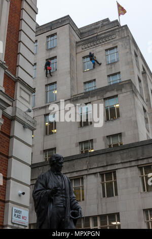 Detergenti per finestre la discesa in corda doppia lungo il lato di un alto multi-story blocco ufficio o edificio in savoy place wc2 nel centro di Londra. la pulizia di vetri in alto. Foto Stock