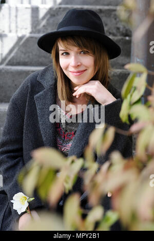 Ritratto di donna sorridente indossando hat seduti da piante Foto Stock