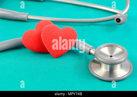 Lo stetoscopio e cuori su sfondo verde nel cuore check up concetto. Foto Stock