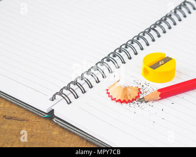 Il fuoco selettivo accessori per ufficio tra cui note book, matita rossa e gialla sharpener su sfondo di legno. L'istruzione e la concezione di business. Foto Stock