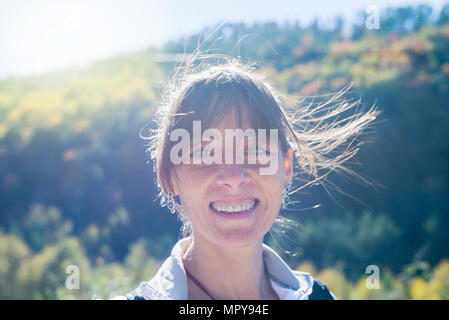 Ritratto di Allegro donna matura con disordinati capelli a forest durante la giornata di sole Foto Stock