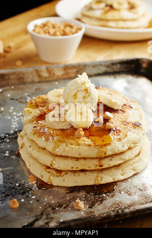 Close-up di pancake con fette di banana e lo sciroppo nel vassoio sul tavolo Foto Stock