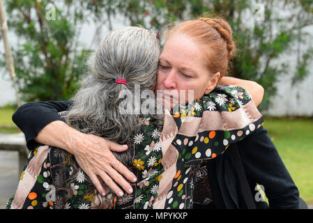 Patricia Gay, 734th aria mobilità Squadron, abbraccia un amico durante il Lt Col. (Ret.) Chuck McManus' funerale a Guam cimitero dei veterani di Aprile 26, 2017 in Piti, Guam. La McManus fu una figura chiave presso Andersen Air Force Base a causa di un suo coinvolgimento durante il linebacker II campagna durante la Guerra del Vietnam. (U.S. Air Force foto di Airman 1. Classe Christopher quaglie) Foto Stock