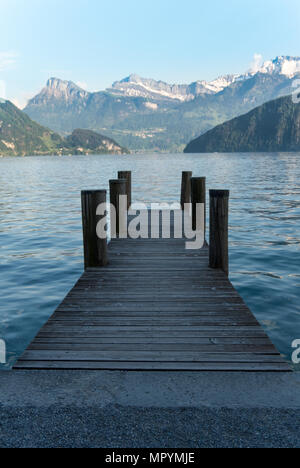 Pier in Weggis, il lago di Lucerna che conducono fuori nell'acqua direttamente verso cime innevate Foto Stock