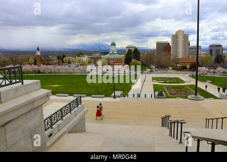 Ragazza in abito rosso a piedi lungo la capitale dello stato dello Utah A Salt Lake City. Il fiore di ciliegio alberi sono in piena fioritura di primavera Foto Stock