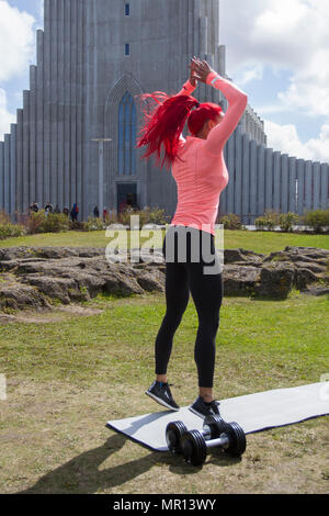 Reykjavík, Islanda. 25/05/2018 Meteo. Pomeriggio di sole nella capitale come Hannah Eden (Eden fitness training online) esegue una routine per un esercizio video, di fronte alla chiesa Hallgrímskirkja che è Reykjavik il punto di riferimento principale. Foto Stock